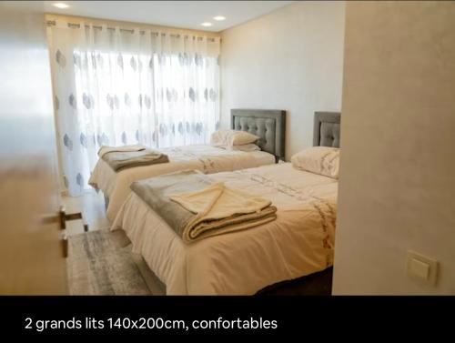 a bedroom with two beds with towels on them at APPARTEMENT 5 étoiles VUE SUR MER in Tangier