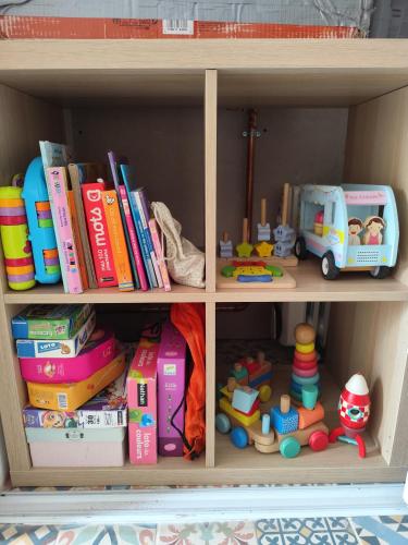 une étagère en bois remplie de jouets et de livres dans l'établissement La Grange aux fées Amnéville, à Amnéville