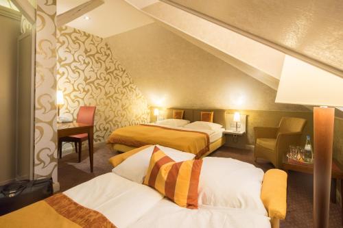 a hotel room with two beds and a chair at Parkhotel Güldene Berge in Weißenfels