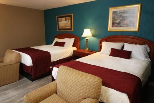 a hotel room with two beds and a chair at American Star Inn - Abilene in Abilene