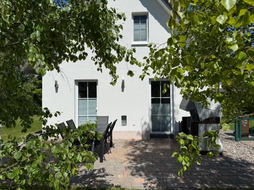 una casa bianca con panchine davanti di Reethaus Sonnenwiese, Haus am Meer mit eingezäuntem Garten, Hunde herzlich willkommen a Glowe