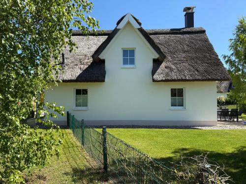 una casa bianca con tetto di paglia di Reethaus Sonnenwiese, Haus am Meer mit eingezäuntem Garten, Hunde herzlich willkommen a Glowe