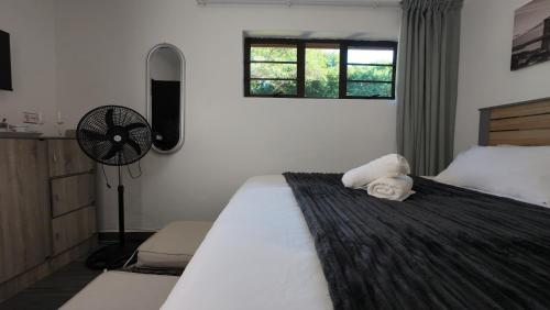 a bedroom with a large white bed with a fan at Grace Avenue Bungalow in Port Edward