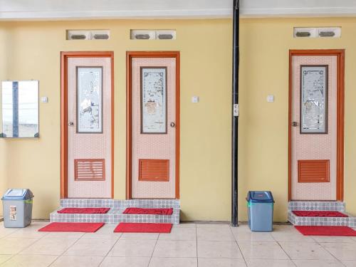 three doors on a building with two trash cans at Palma Villa Homestay Klaten in Kuwoso