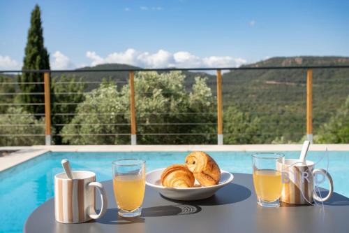 une table avec une assiette de pain et des verres de jus d'orange dans l'établissement Superb neo-Provençal villa with swimming pool air conditioning and view, à Bagnols-en-Forêt