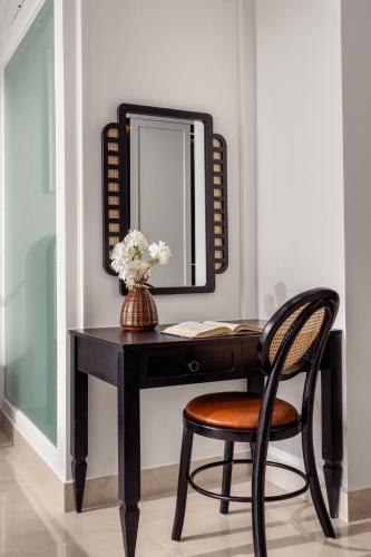 a black desk with a mirror and a chair at ELC Boutique Hoi An Hotel in Hoi An