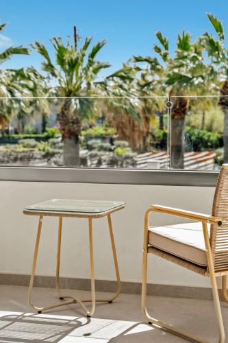 a table and a chair in front of a window at Ammos Boutique Apartments & Suites in Malia