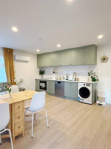 a kitchen with a wooden table and white chairs at Free parking a fully renovated century old building, just a 5 minute drive to the city center Unit 4 in Auckland