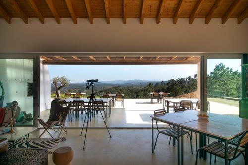 a room with tables and chairs and a large glass door at Vale das Estrelas in São Teotónio