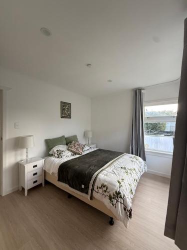 a white bedroom with a bed and a window at Free parking a fully renovated century old building, just a 5 minute drive to the city center Unit 4 in Auckland