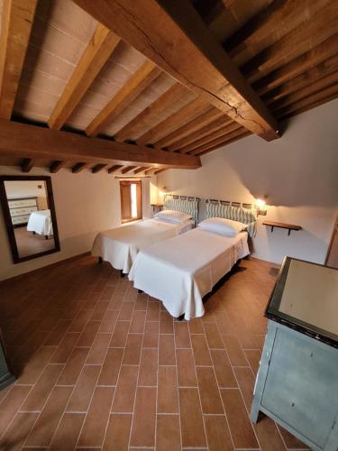 two beds in a room with wooden ceilings at Agriturismo Cardella in Piobbico