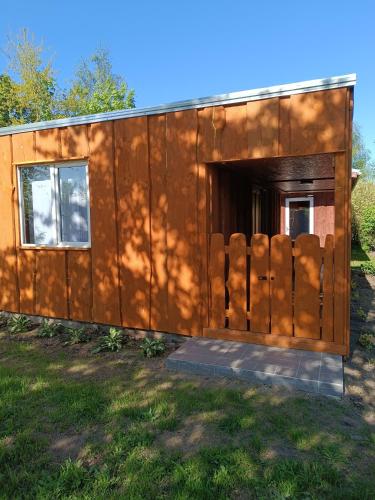 a brown building with a door in the grass at Atpūtas vieta Buki in Ventspils