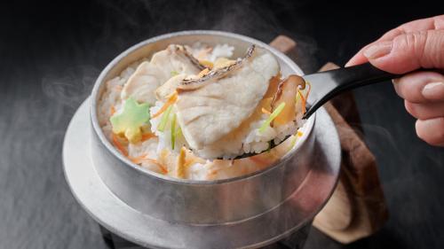 a person is eating food in a pot with a spoon at Rantei in Sendai