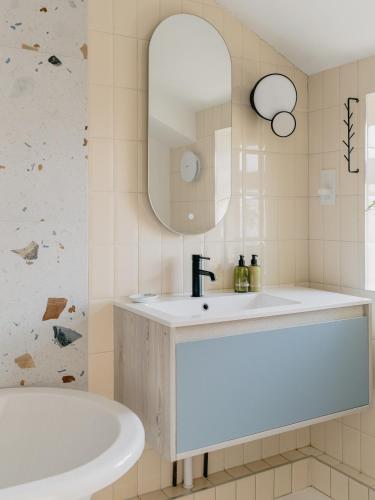 a bathroom with a sink and a tub and a mirror at Rose Garden Maisonette in Falmouth
