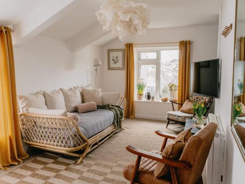a living room with a couch and a tv at Rose Garden Maisonette in Falmouth