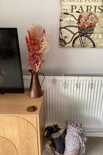 a room with a tv and a vase on a cabinet at Lorton Villa with a Log Burner in Saint Helens