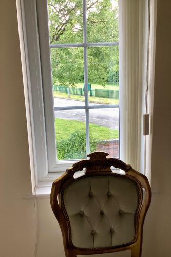 a chair sitting in front of a window at Lorton Villa with a Log Burner in Saint Helens