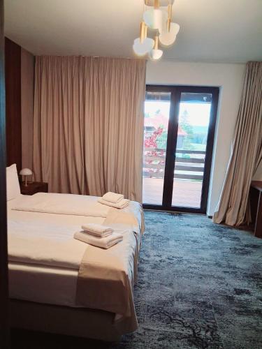 a hotel room with two beds and a large window at Monterai Resort in Poiana Brasov
