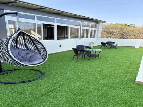 a patio with chairs and a hammock on the grass at Housr 36 Studio Rooms Bangalore Near Leela Palace in Bengaluru