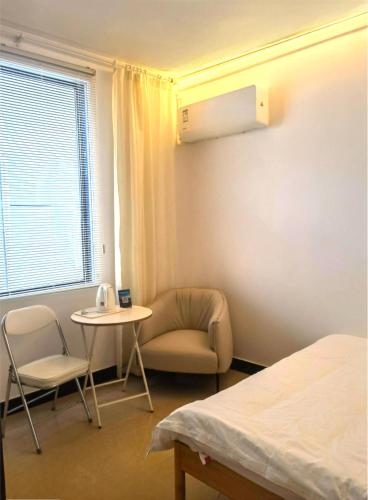 a room with a bed and a chair and a table at Up Apartment in Jingdezhen