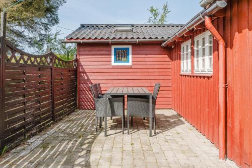 a patio with a table and chairs in front of a red building at Bedstefars lille skovhus in Hjørring