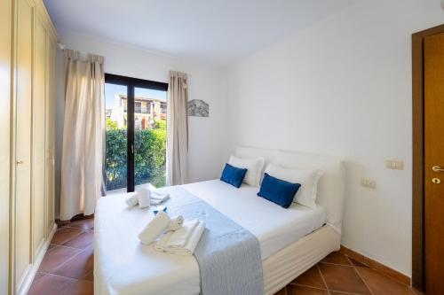a bedroom with a large white bed with blue pillows at Green Residence Bados Mare in Olbia