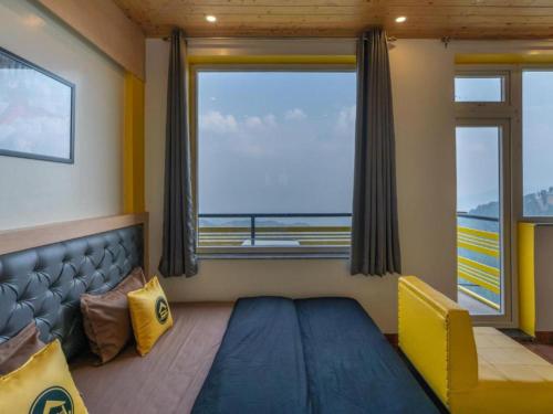 Un dormitorio con una cama y una ventana grande. en The Hosteller Kufri, Shimla, en Kūfrī