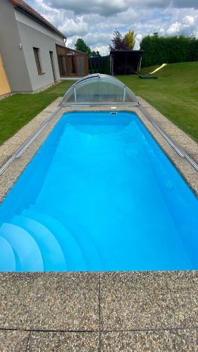 a blue swimming pool in a yard with a house at Apartmány Vojta in Telč
