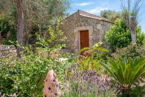 a stone house with a garden with flowers at Agroturisme Es Racó De Maria in Maria de la Salut