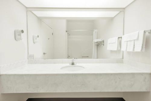 a white bathroom with a sink and a mirror at Days Inn by Wyndham Montgomery in Montgomery