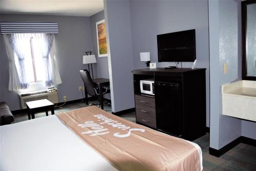 a hotel room with a bed and a flat screen tv at Days Inn by Wyndham Montgomery in Montgomery