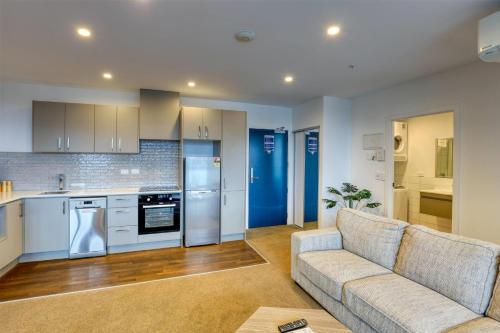a living room with a couch and a kitchen at Ramada Suites by Wyndham Queenstown Remarkables Park in Queenstown