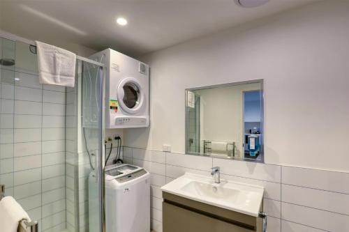 a bathroom with a sink and a washing machine at Ramada Suites by Wyndham Queenstown Remarkables Park in Queenstown