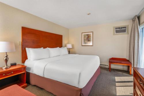 a hotel room with a large white bed and a window at Travelodge by Wyndham Gananoque in Gananoque