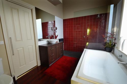 y baño con bañera, lavabo y azulejos rojos. en Clement House, en Benalla