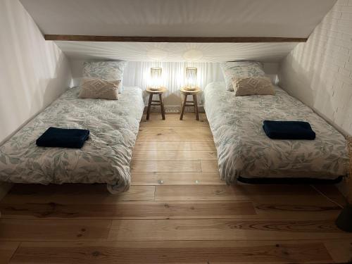 twee bedden in een kleine kamer met twee tafels bij Sous le chemin de Paris in Milly-la-Forêt