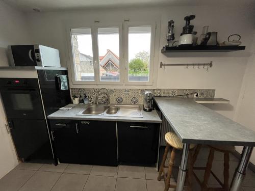een keuken met een spoelbak en een aanrechtblad bij Sous le chemin de Paris in Milly-la-Forêt