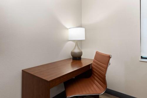 a desk with a lamp and a chair at Hawthorn Extended Stay by Wyndham College Station South in College Station