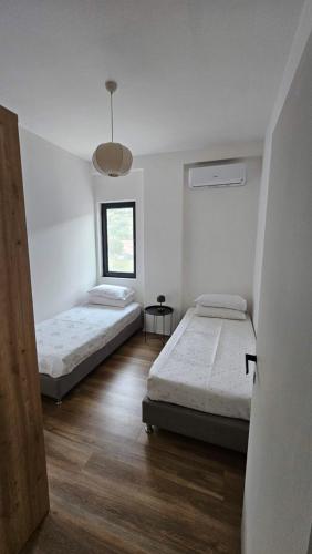 two beds in a room with white walls and wooden floors at Modern apartment with sea views in Vlorë
