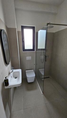 a bathroom with a sink and a toilet and a shower at Modern apartment with sea views in Vlorë