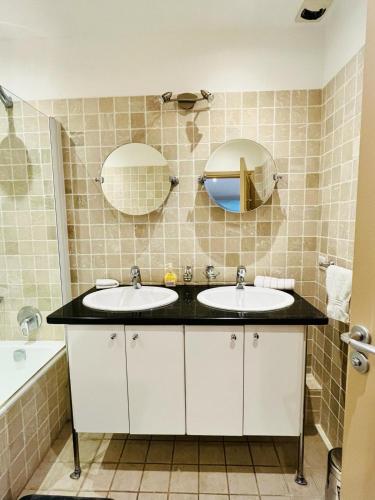 une salle de bain avec deux lavabos et deux miroirs dans l'établissement Golden Triangle 2Br/2Ba, à Cannes