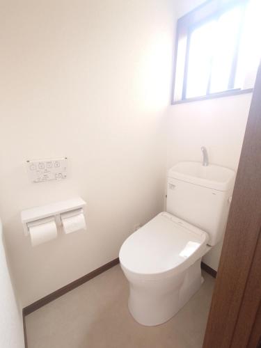 a white bathroom with a toilet and a window at Chiba Gateway House in Chiba