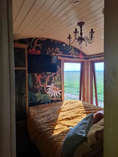 a bedroom with a bed and a chandelier and a window at Sycamore and Stars Off Grid Retreat in Grasby