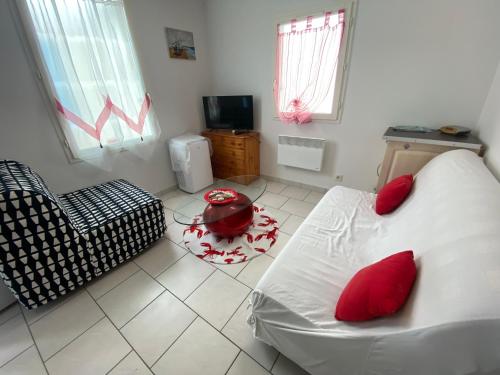 - un salon avec un canapé blanc et des oreillers rouges dans l'établissement Studio bord de mer Max 4 personnes, à Saint-Hilaire-de-Riez