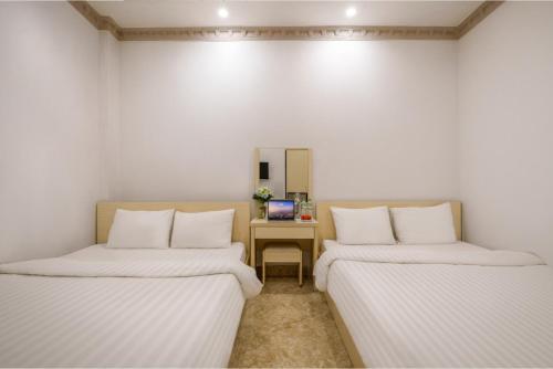 two beds in a room with a desk and a mirror at AN Boutique Hotel in Da Lat