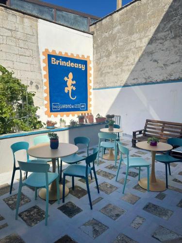 een patio met tafels en stoelen en een bord aan de muur bij Giardino del Geco in Brindisi