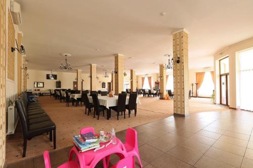 a large dining room with a pink table and chairs at Pensiunea Cavaler in Baile Felix