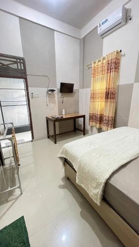 a bedroom with a bed and a desk and a television at Homestay Yaa Syafi in Bireun