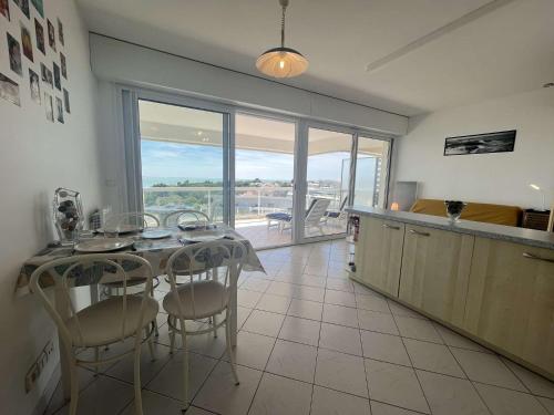 une cuisine avec une table et des chaises ainsi qu'une grande fenêtre dans l'établissement Appartement Studio LA ROCHELLE - LR110-G53, à La Rochelle