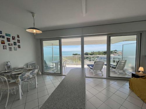 - un salon avec une table et des chaises et une vue sur l'océan dans l'établissement Appartement Studio LA ROCHELLE - LR110-G53, à La Rochelle